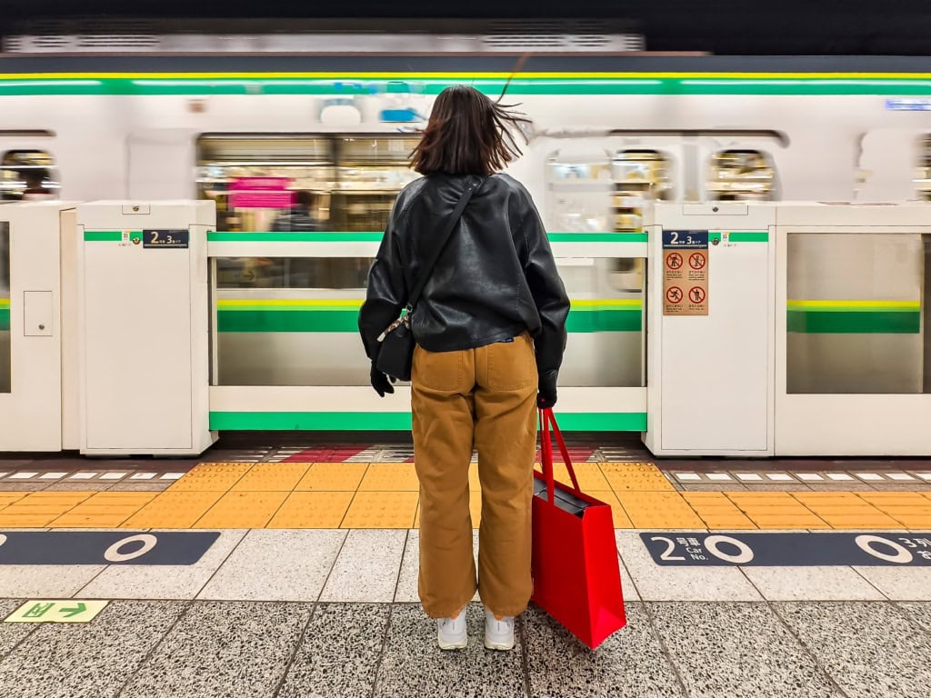 Eine Frau steht an einem Bahnsteig in Tokio.