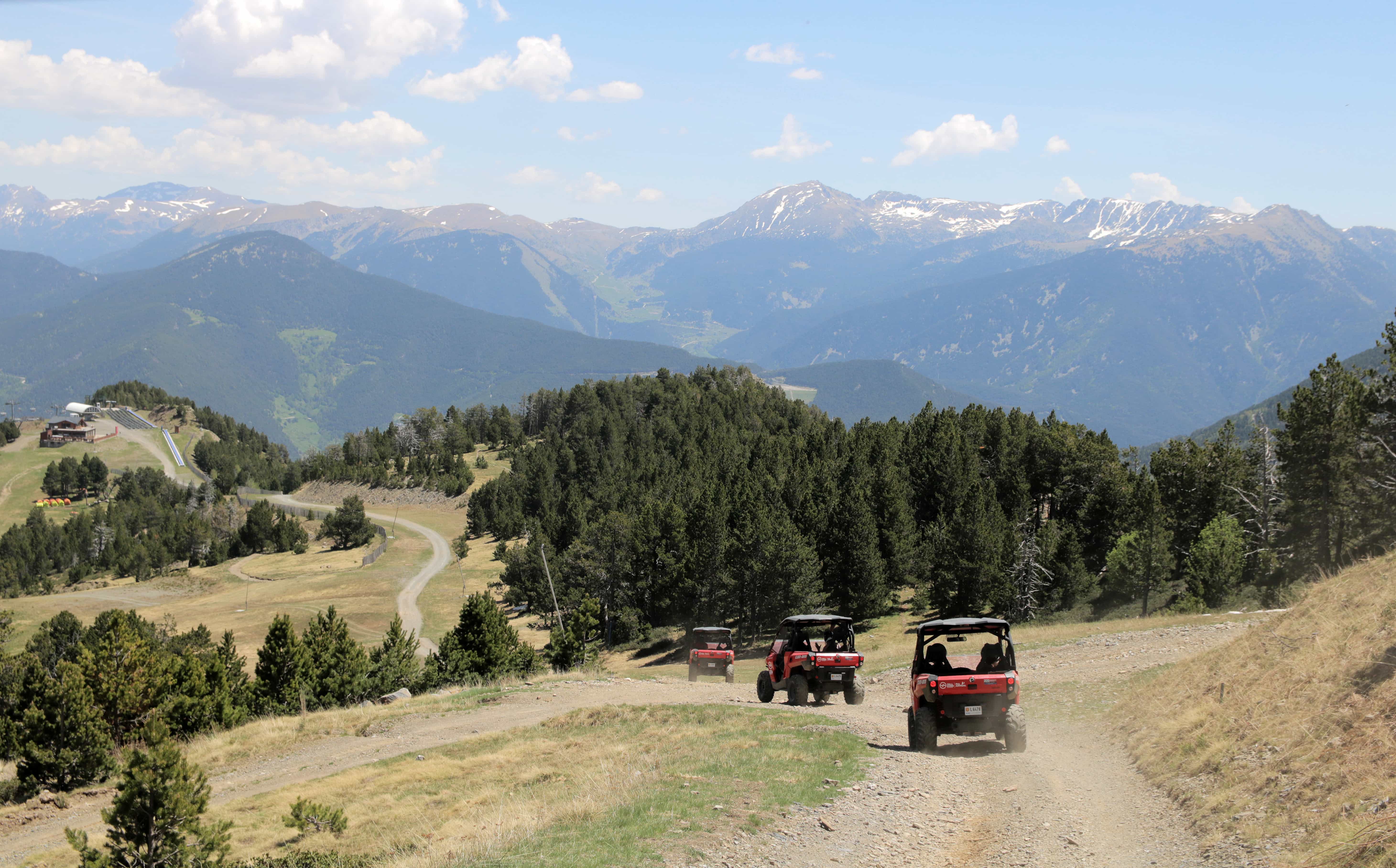 Vier rote Buggies heizen mit Bergpanorama über Schotterpiste 