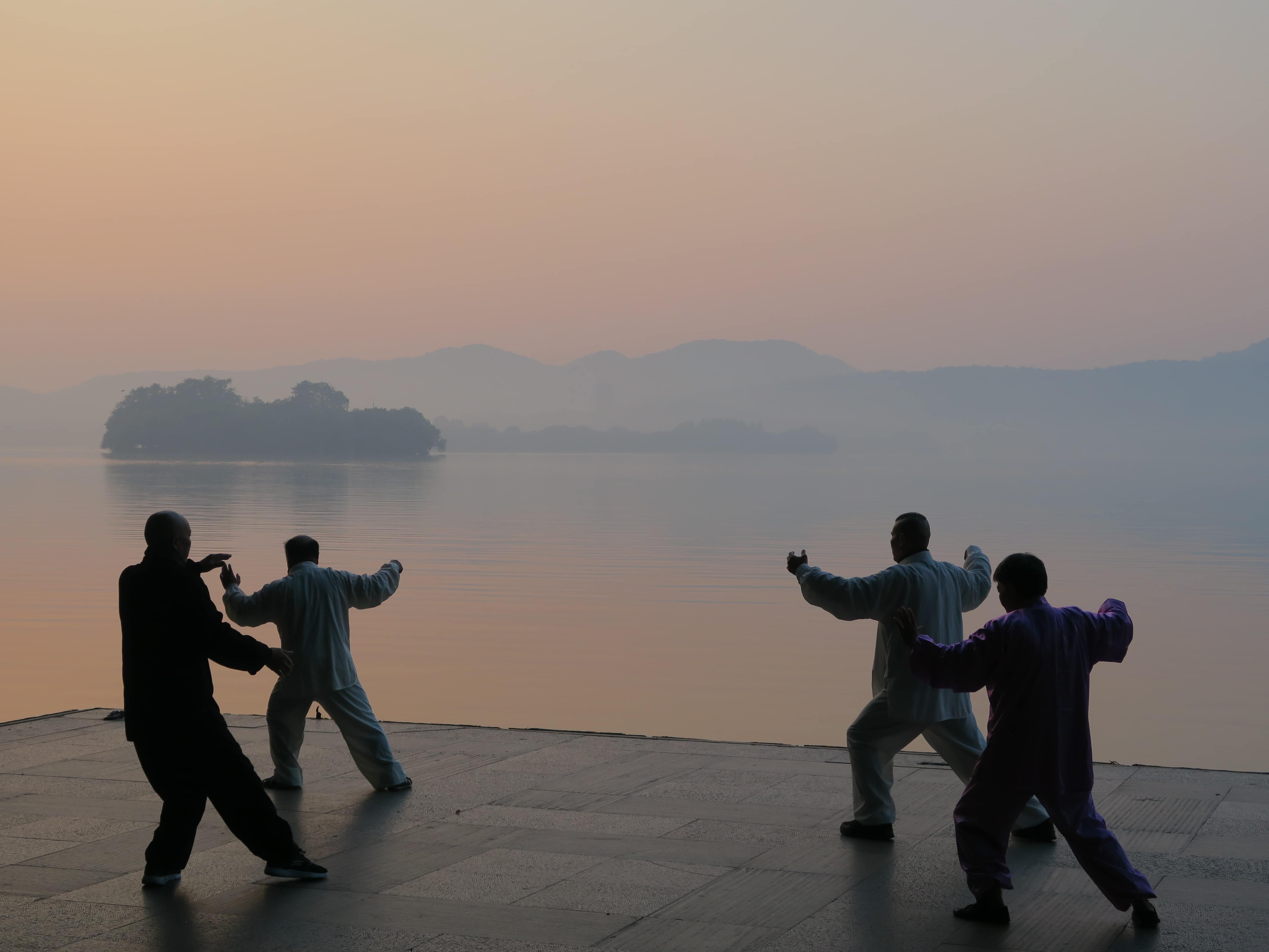 Vier Tai Chi-Kämpfer bei Sonnenaufgang an See