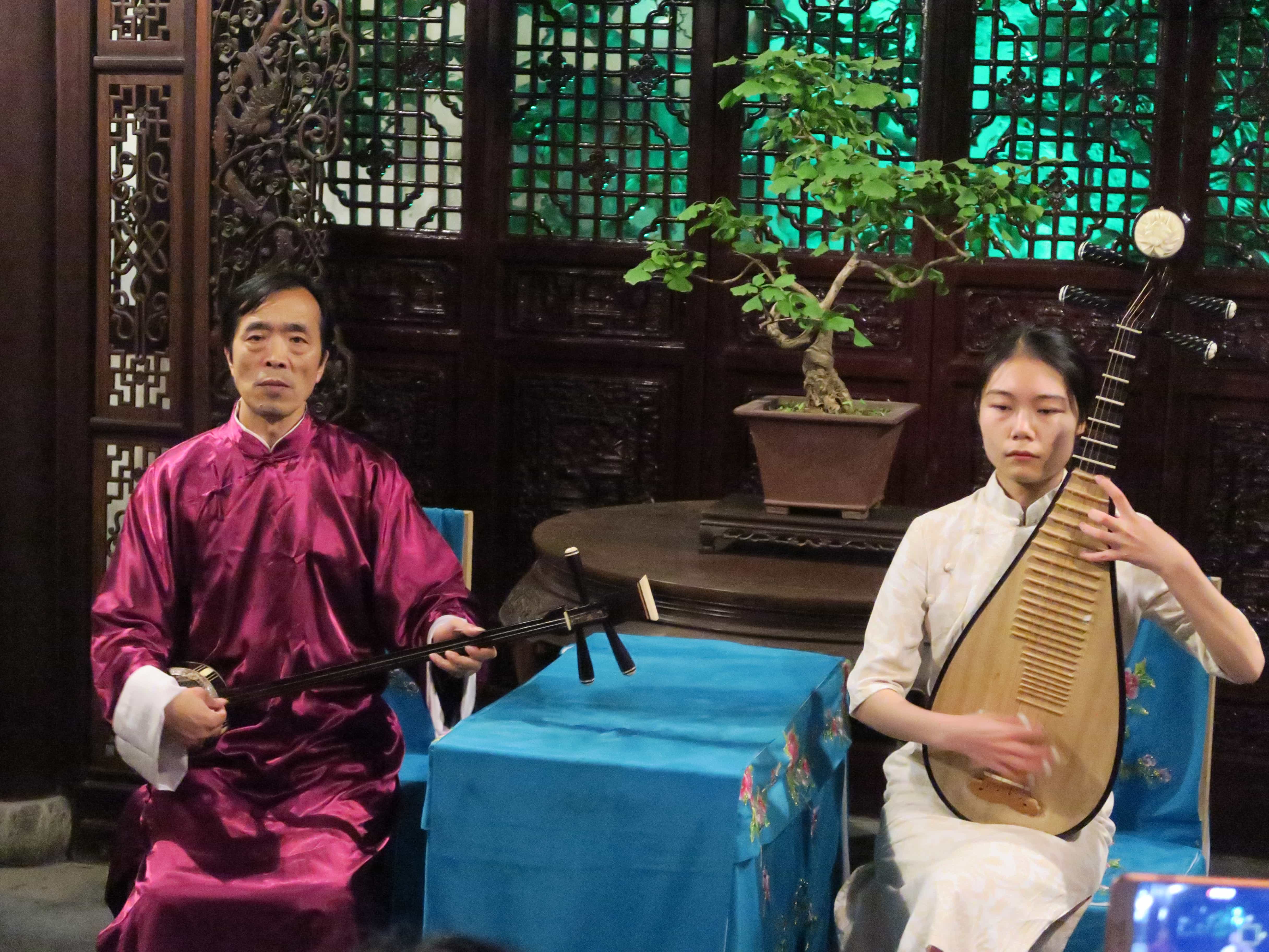 Zwei Chinesen (Mann und Frau) spielen in traditionellem Pavillion Instrumente