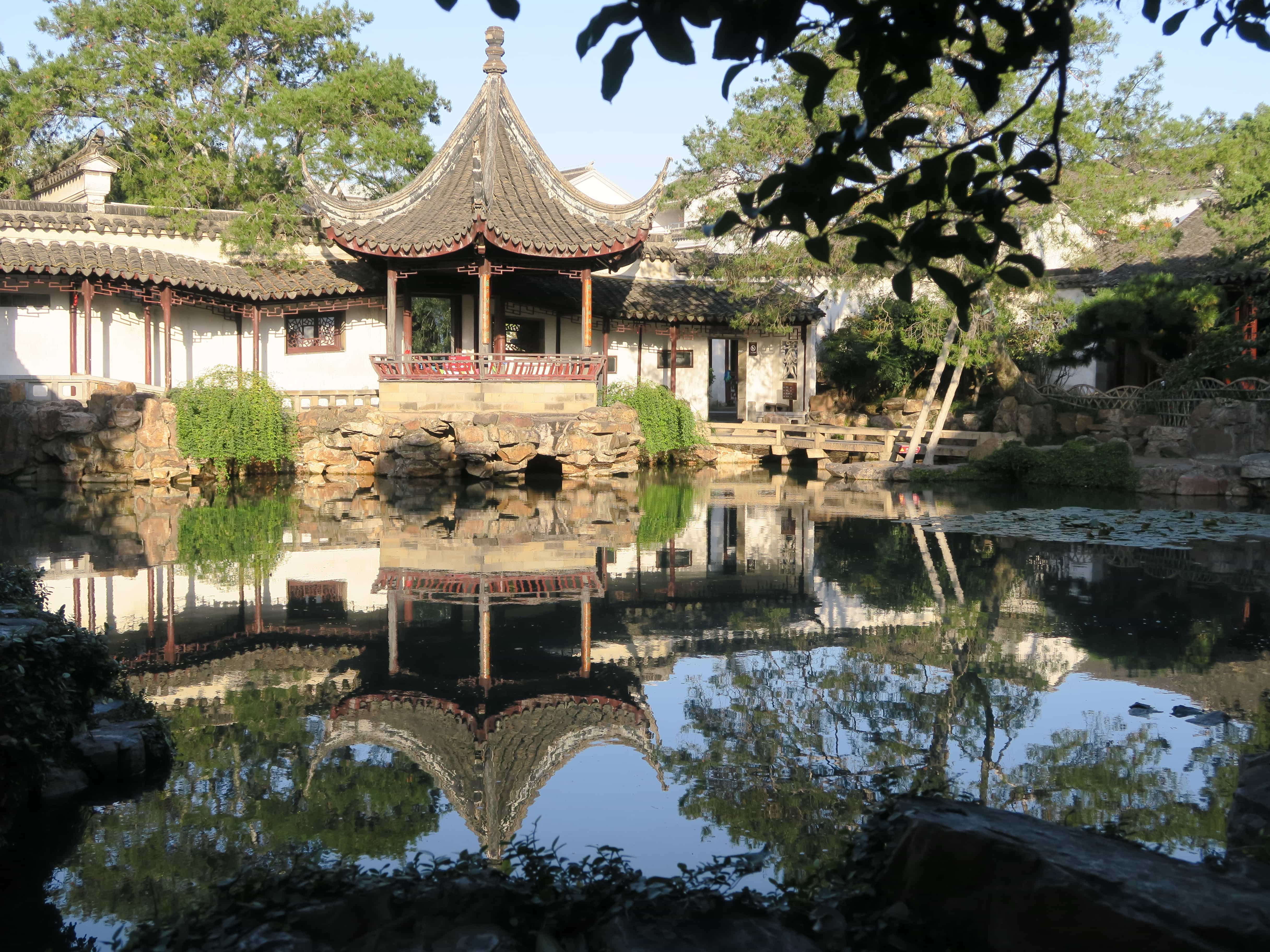 Pavillon am Fuße eines Sees mit Spiegelung der Landschaft in einem Garten in China