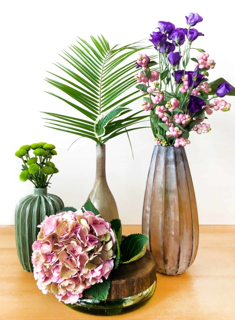 vier Vasen in Naturtönen und verschiedenen Formen sowie Blumen