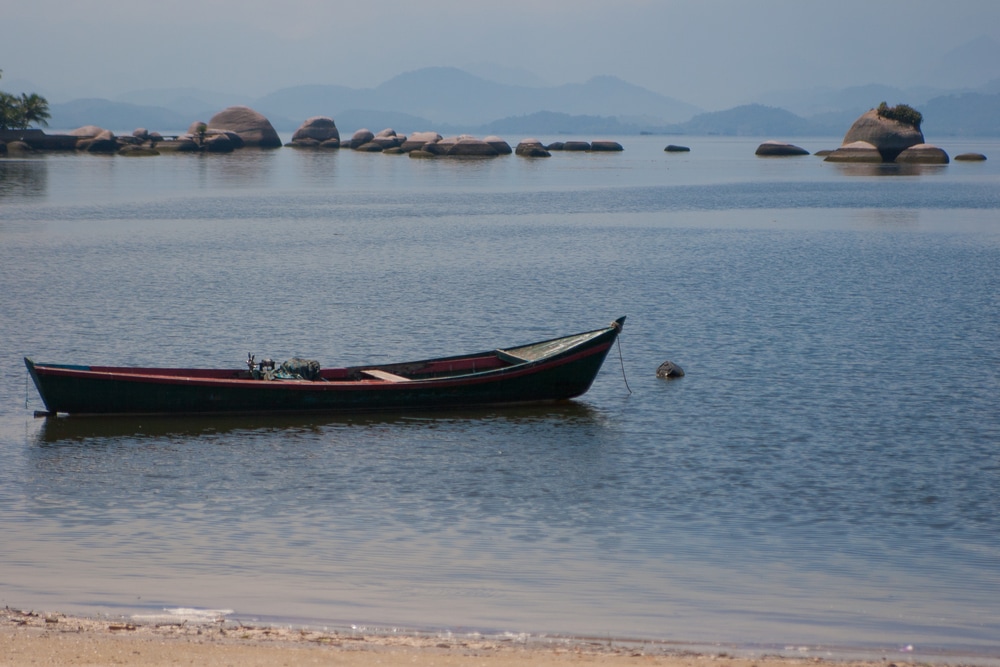Kleines Holzboot in seichtem tropischen Wasser mit Felsen 