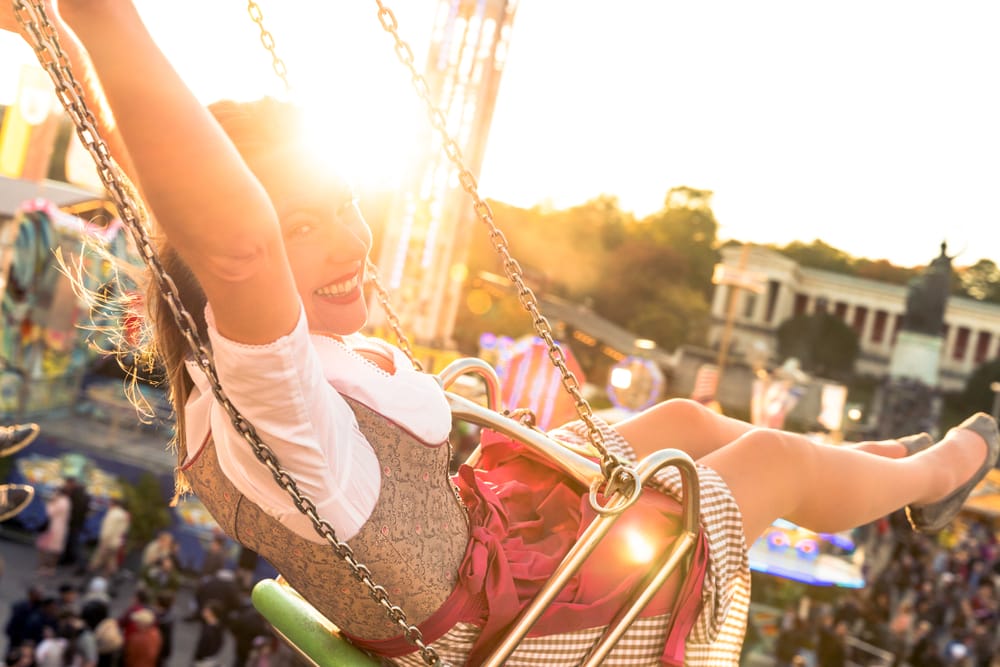 Frau im Dirndl auf einem Karussell auf dem Oktoberfest in München