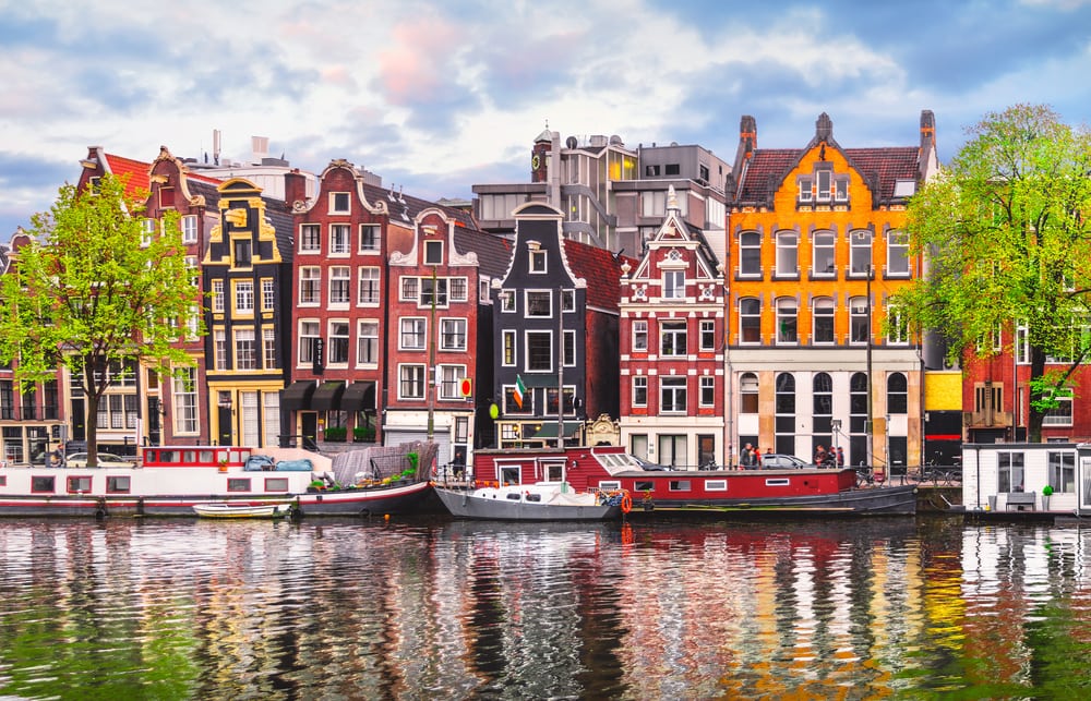 Die alten, bunten Häuser von Amsterdam spiegeln sich im Wasser der Amstel