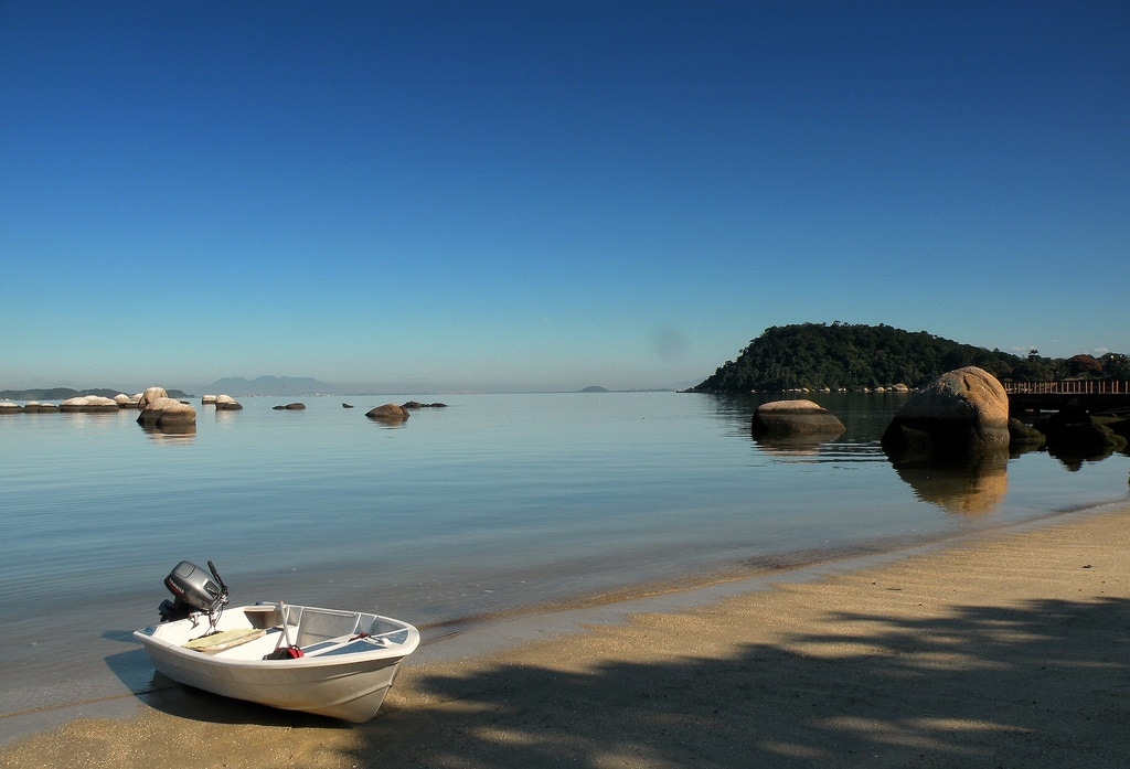 Tropischer Strand mit seichtem Wasser und kleinem Boot.