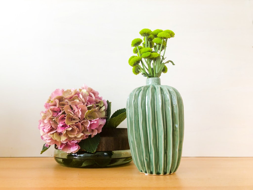 zwei verschiedene Vasen, eine mit Holz, eine aus Keramik mit schönen blumen