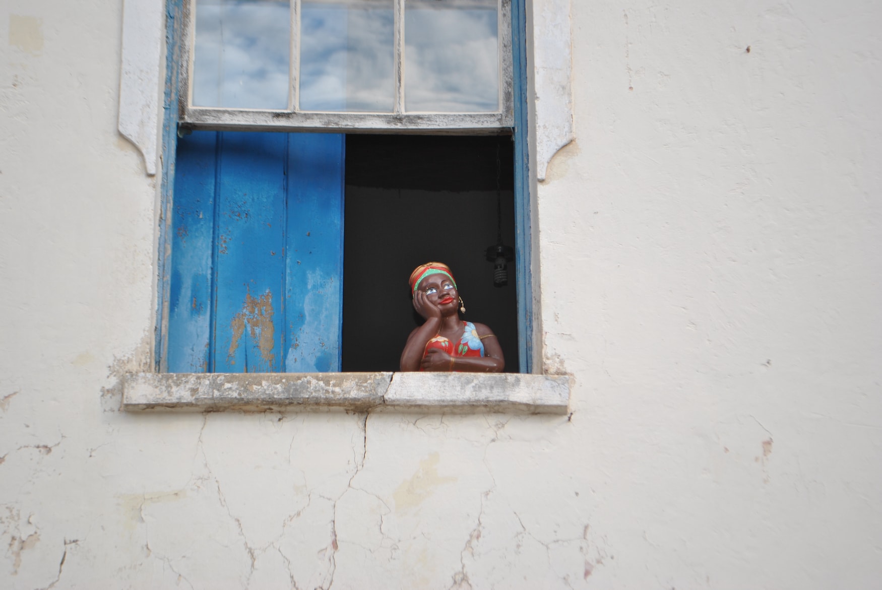 Schwarze Frauenfigur guckt aus Fenster in einem Souvenir-Shop in Salvador in Bahia, Brasilien