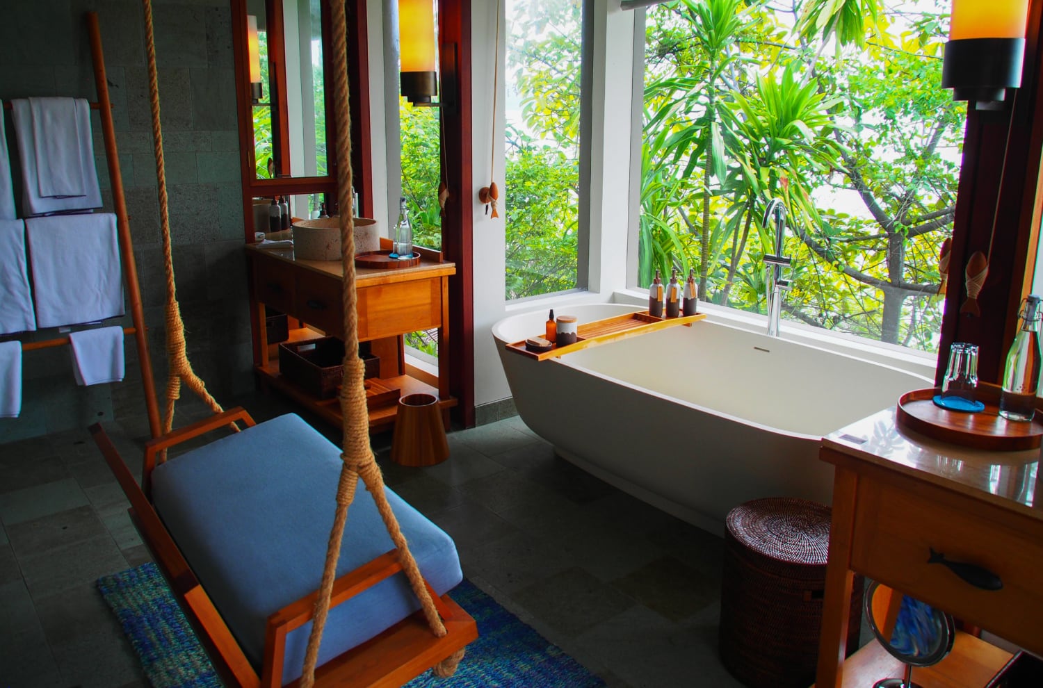 Luxusbadezimmer mit Badewanne mit Blick in die Tropen und Schaukel in Bad