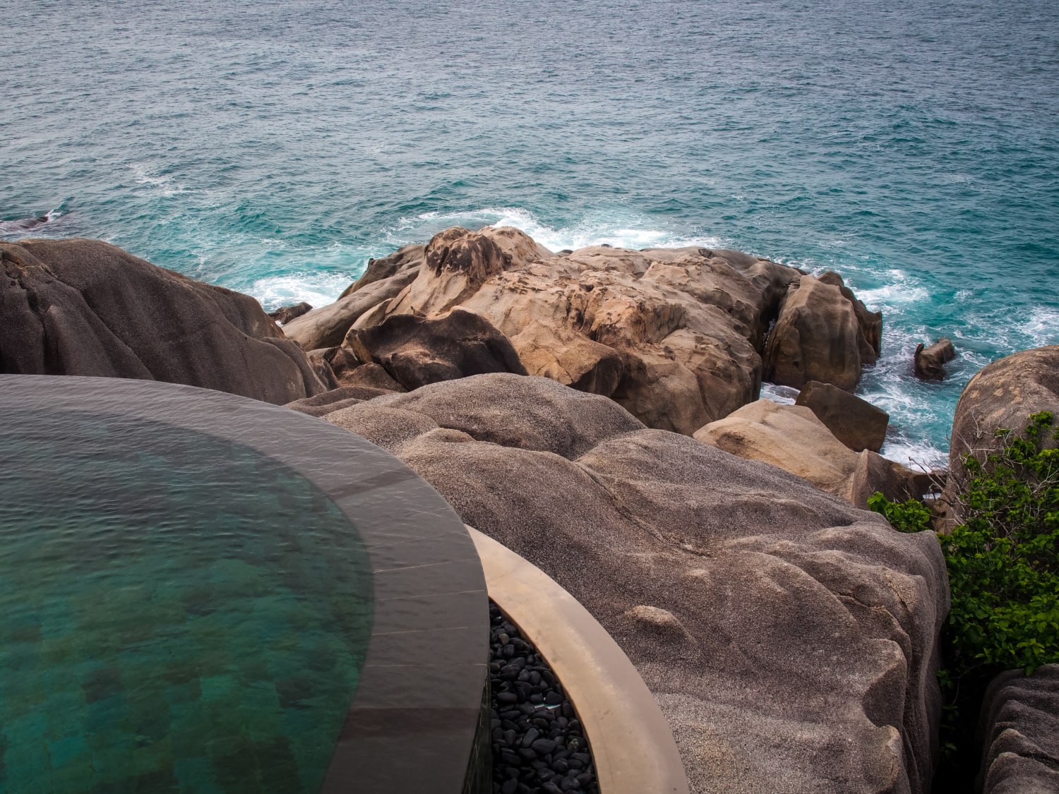 Infinity-Pool mit Blick auf schroffe Felsen und Meer