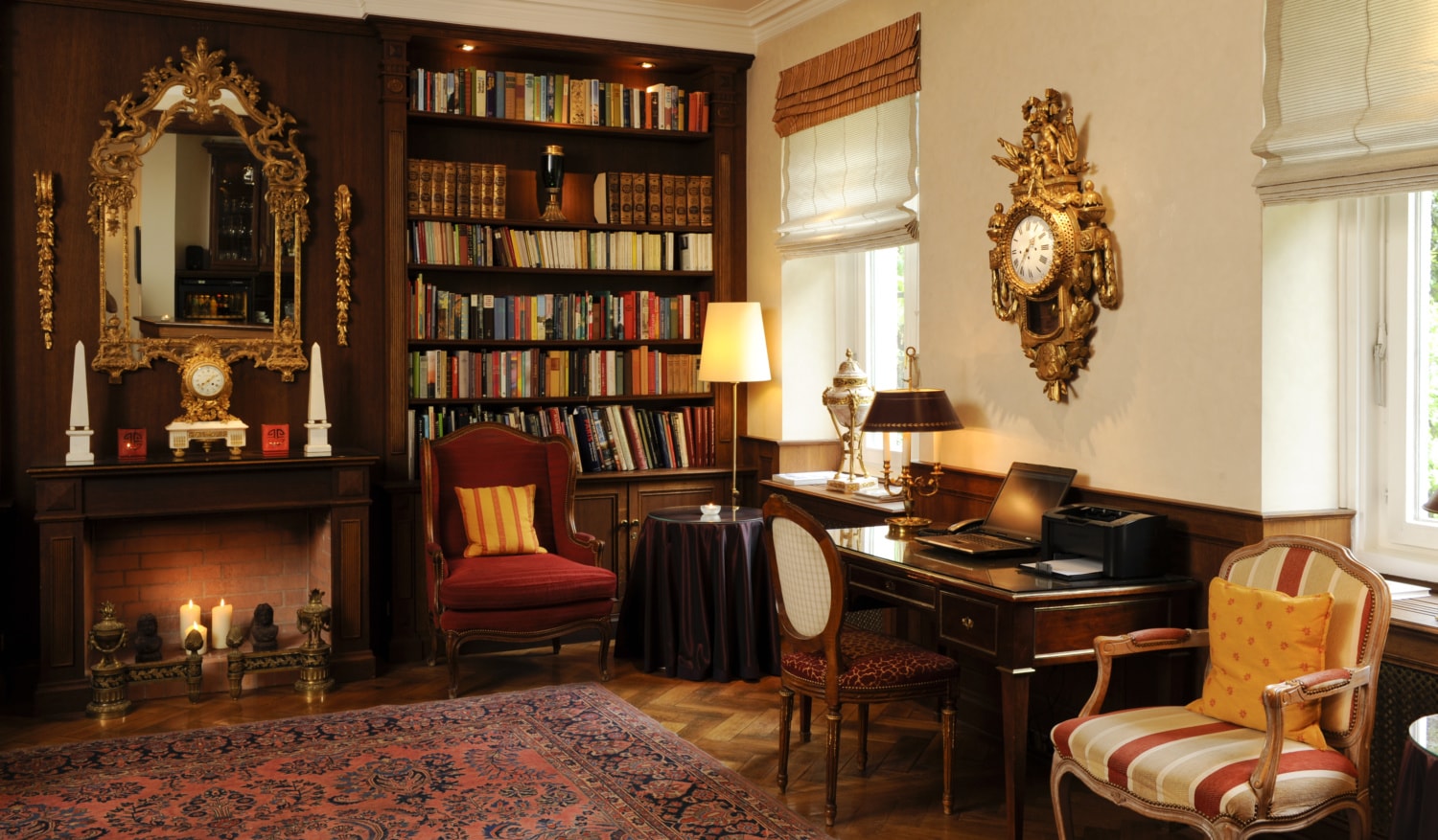 Gemütlicher Raum mit Bücherregal, Sesseln, orientalischem Teppich und altem Schreibtisch