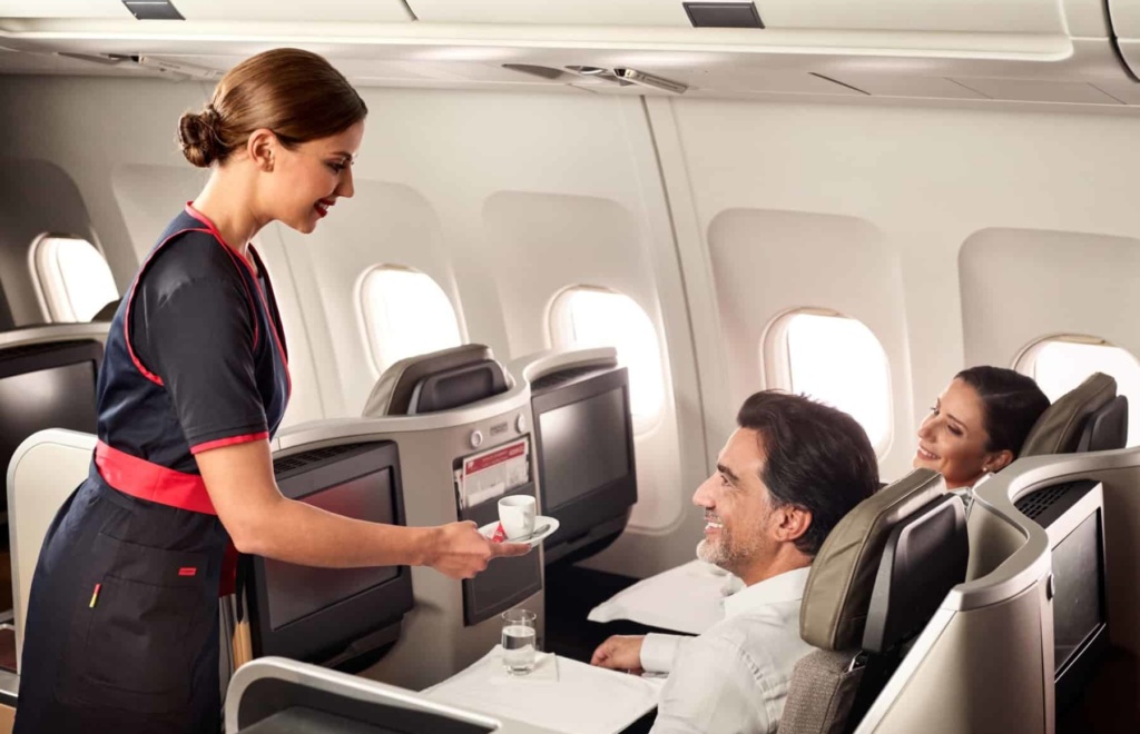 Flugbegleiterin der TAP bedient zwei Passagiere in der Business Class
