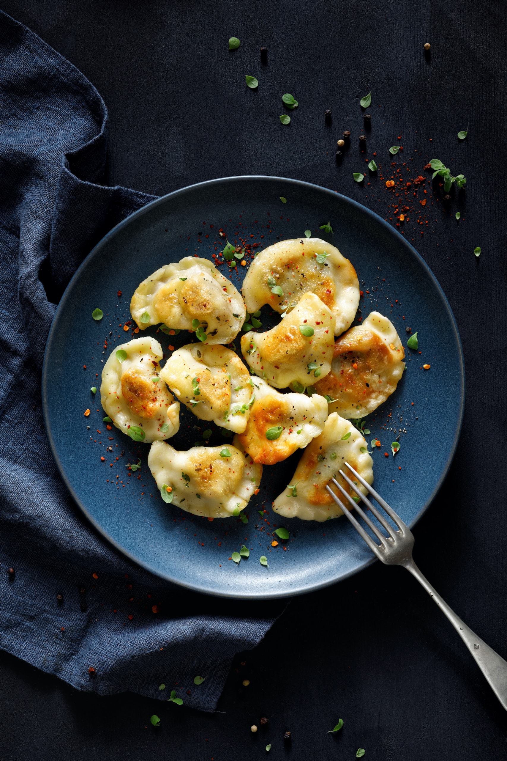 Pierogi angerichtet auf einem dunklen Teller