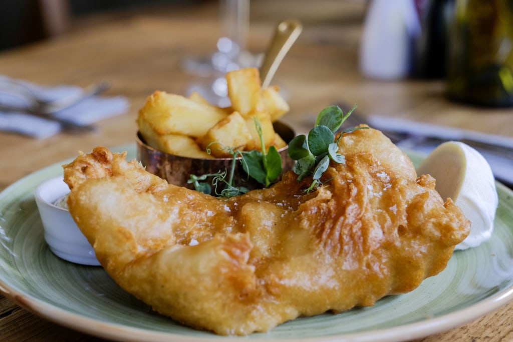 Eine Portion Fish'n'Chips angerichtet auf Teller in einem Pub in England