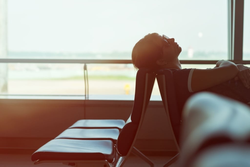 frau schläft auf sitz im flughafen gebäude