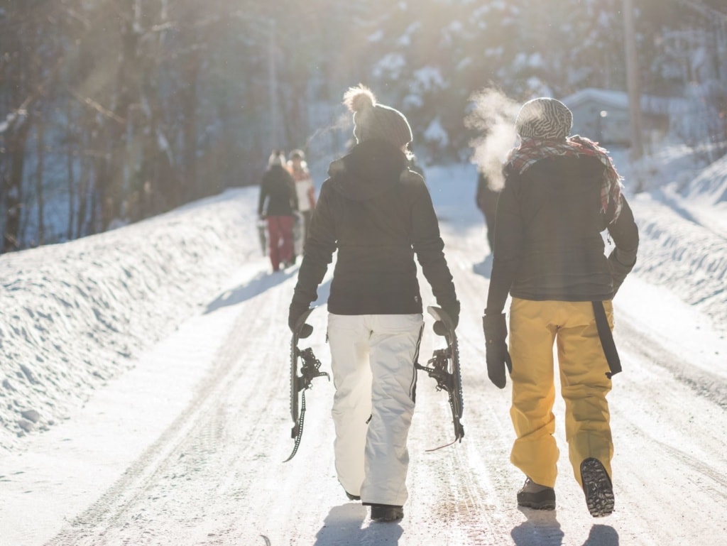 Zwei Skifahrerinnen laufen einen Weg entlang