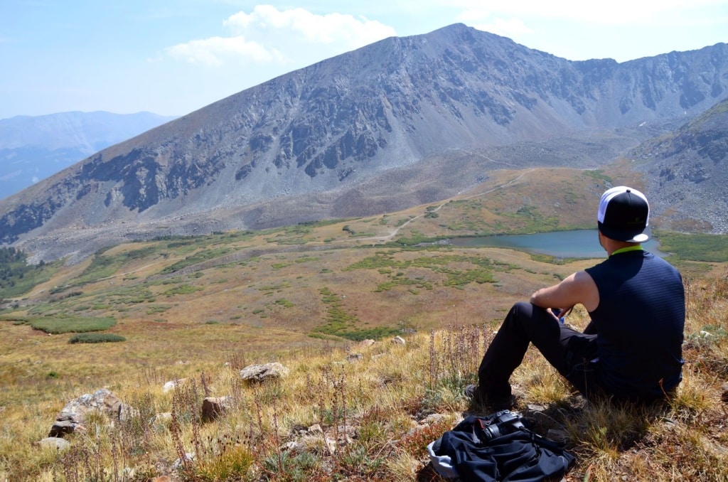 Wanderer blickt sitzend auf Panorama und See in Colorado