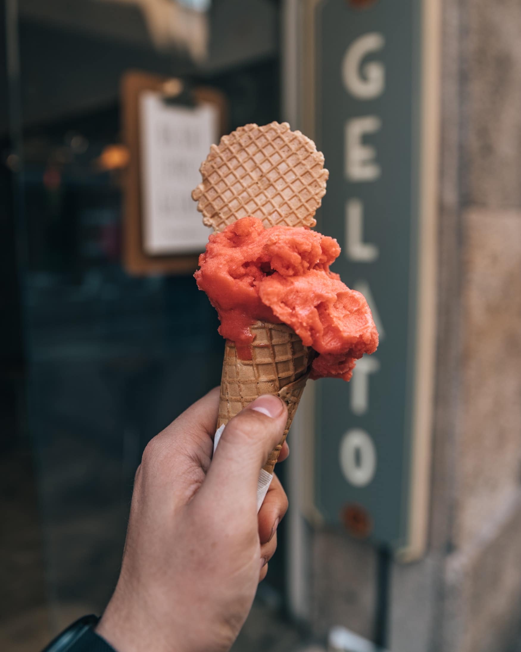 Mann hält Erdbeereis in die Kamera aus einer gelateria in Italien