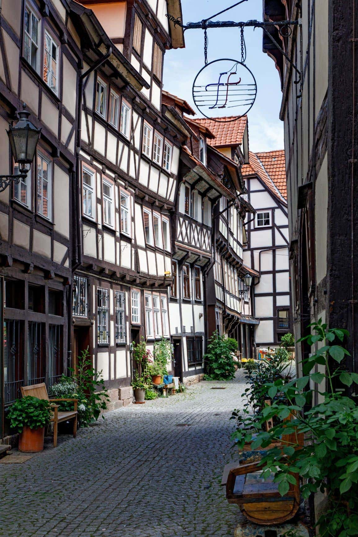 Eine Gasse in der mittelalterlichen Altstadt von Hann. Münden, mit hübschen Fachwerkfassaden. Vor einer Tür hängt ein metallenes Schild, das die Buchstaben "ff" zeigt.
