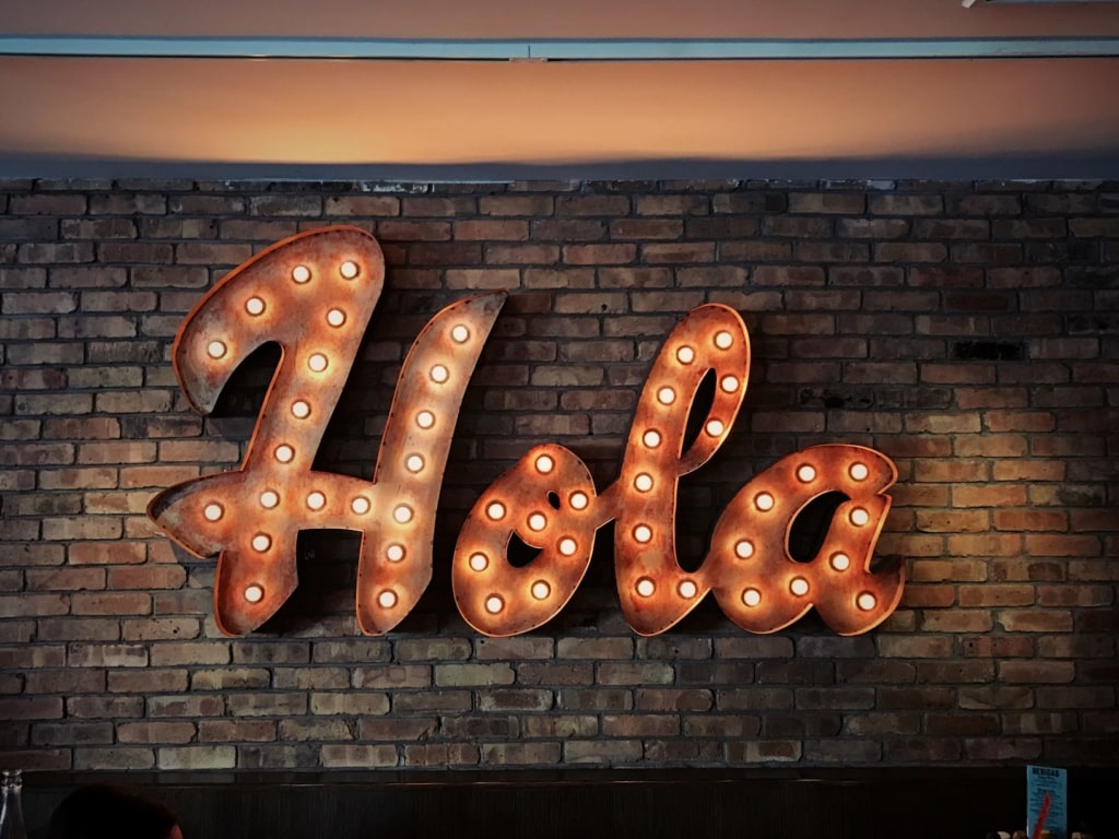 Hola-Schriftzug vor Backstein-Ziegelwand