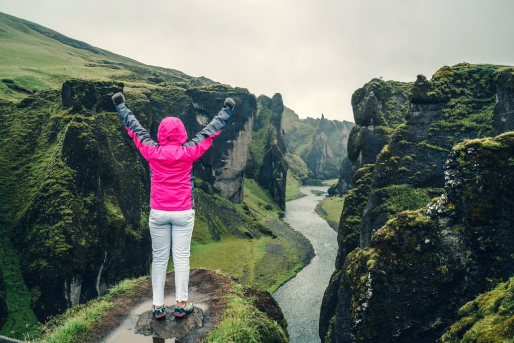Frau mit hochgestreckten Armen am Fjadrárgljúfur Canyon in Island