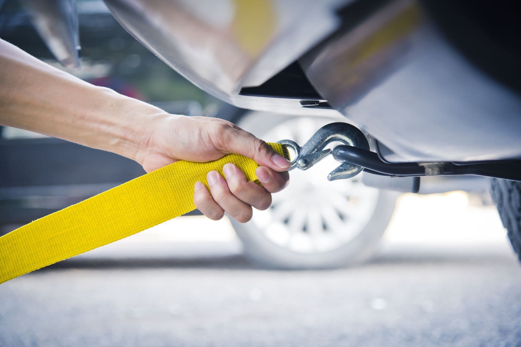 Person befestigt Abschleppseil an Auto