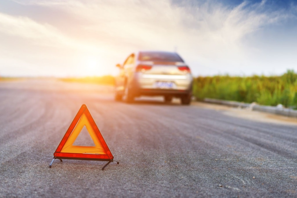 Warndreick auf Straße, im Hintergrund Auto