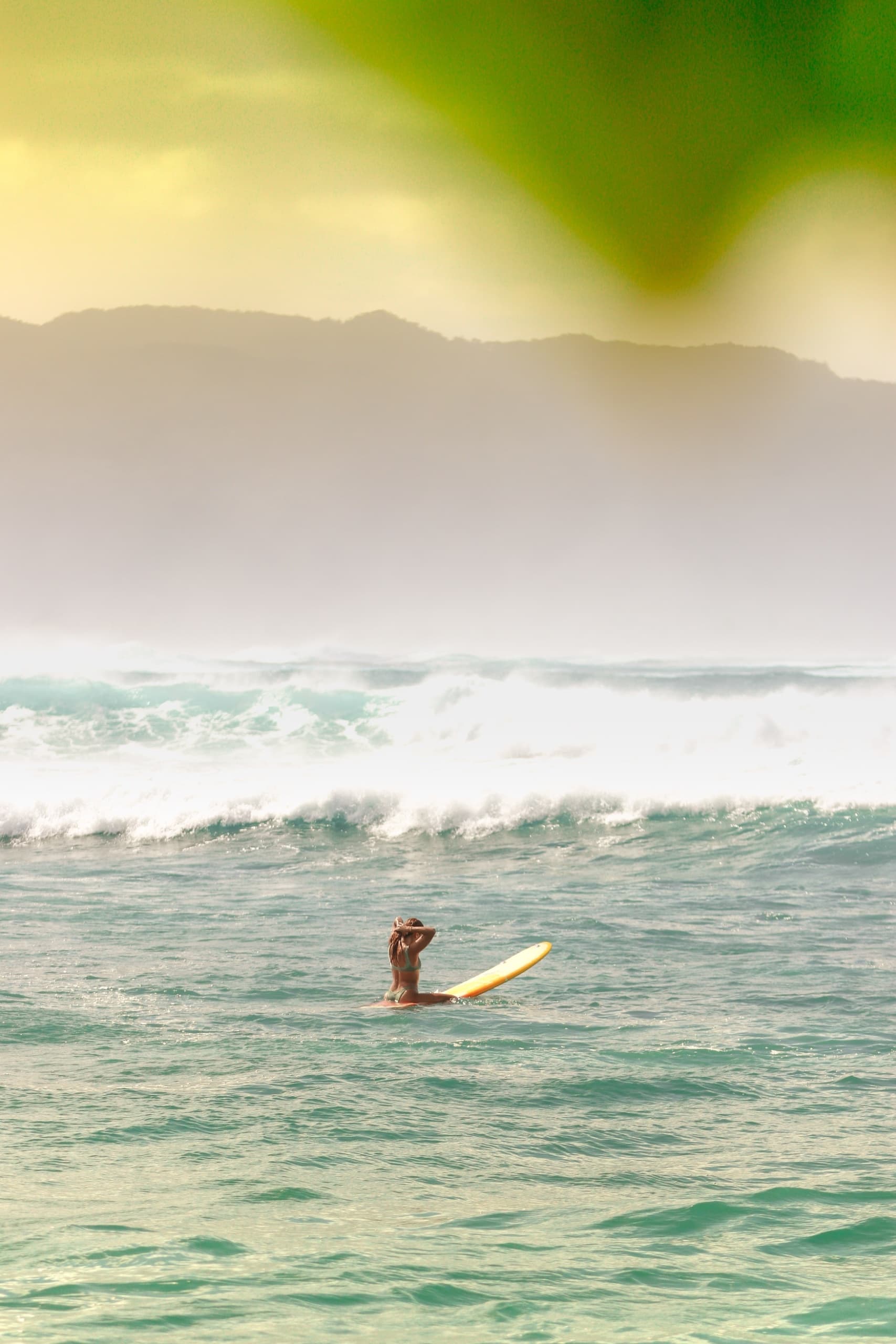 Surferin in den Wellen vor einer Insel von Hawaii