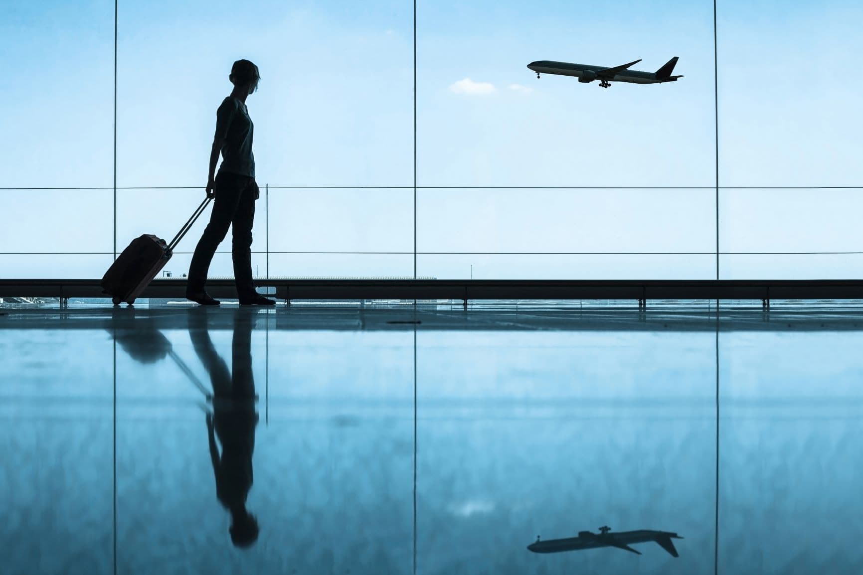 Frau mit Rollkoffer im Flughafen