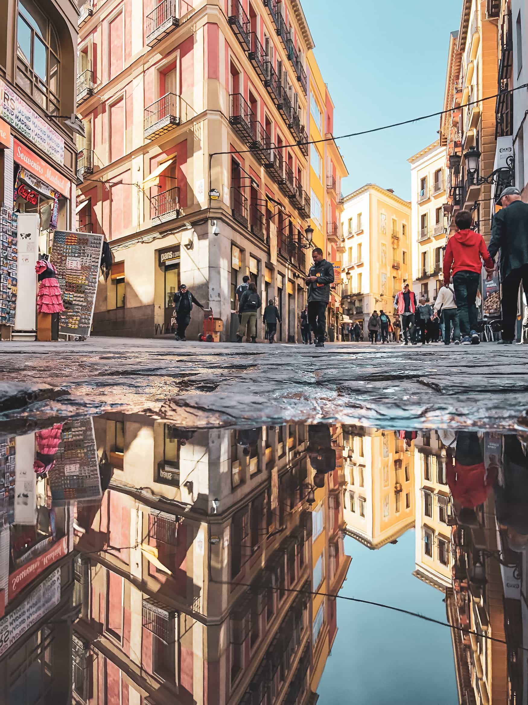 Häuserfassaden der Altstadt in Madrid spiegeln sich in Pfütze