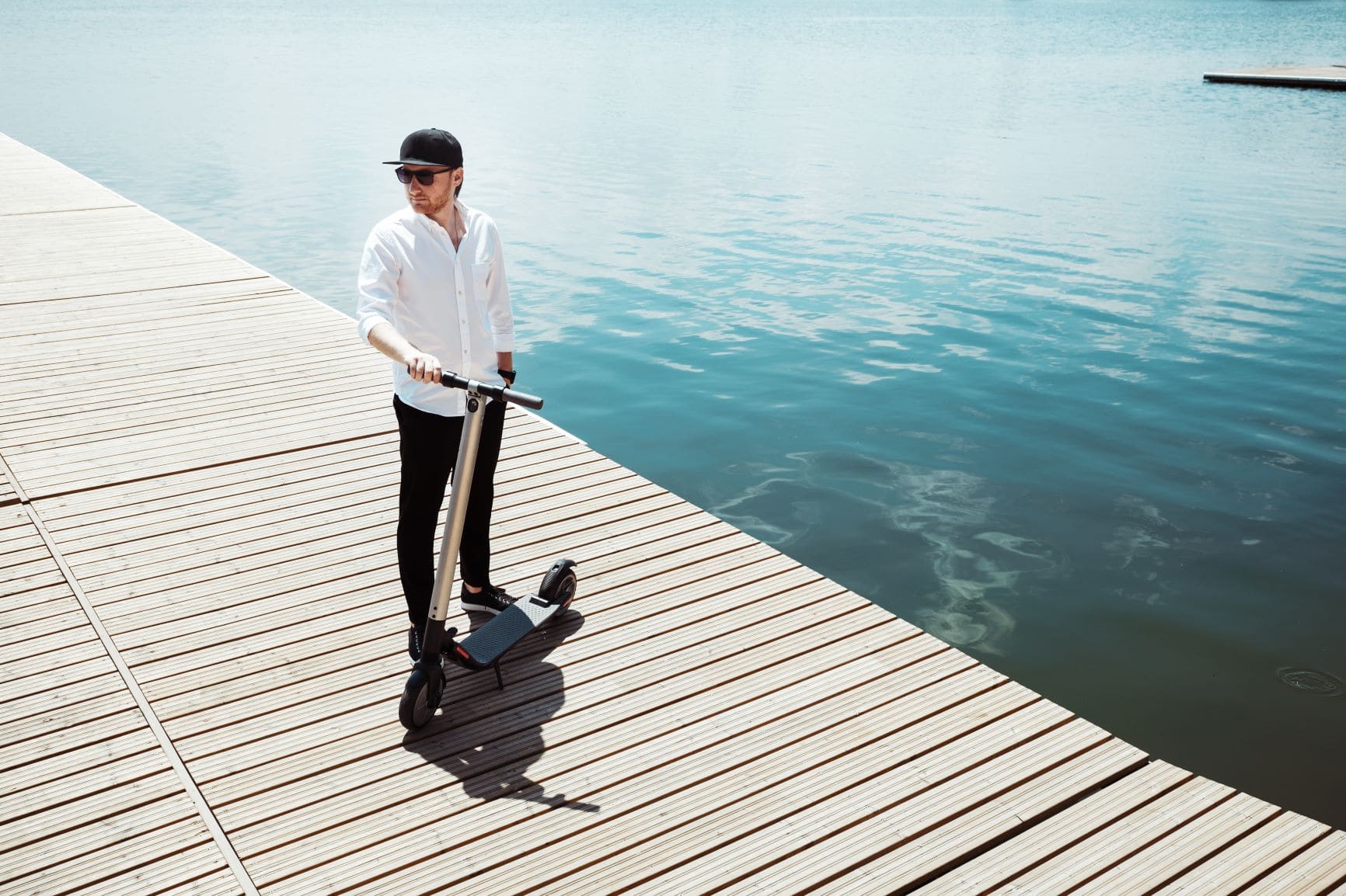 Mann mit E-Scooter am See-Steg