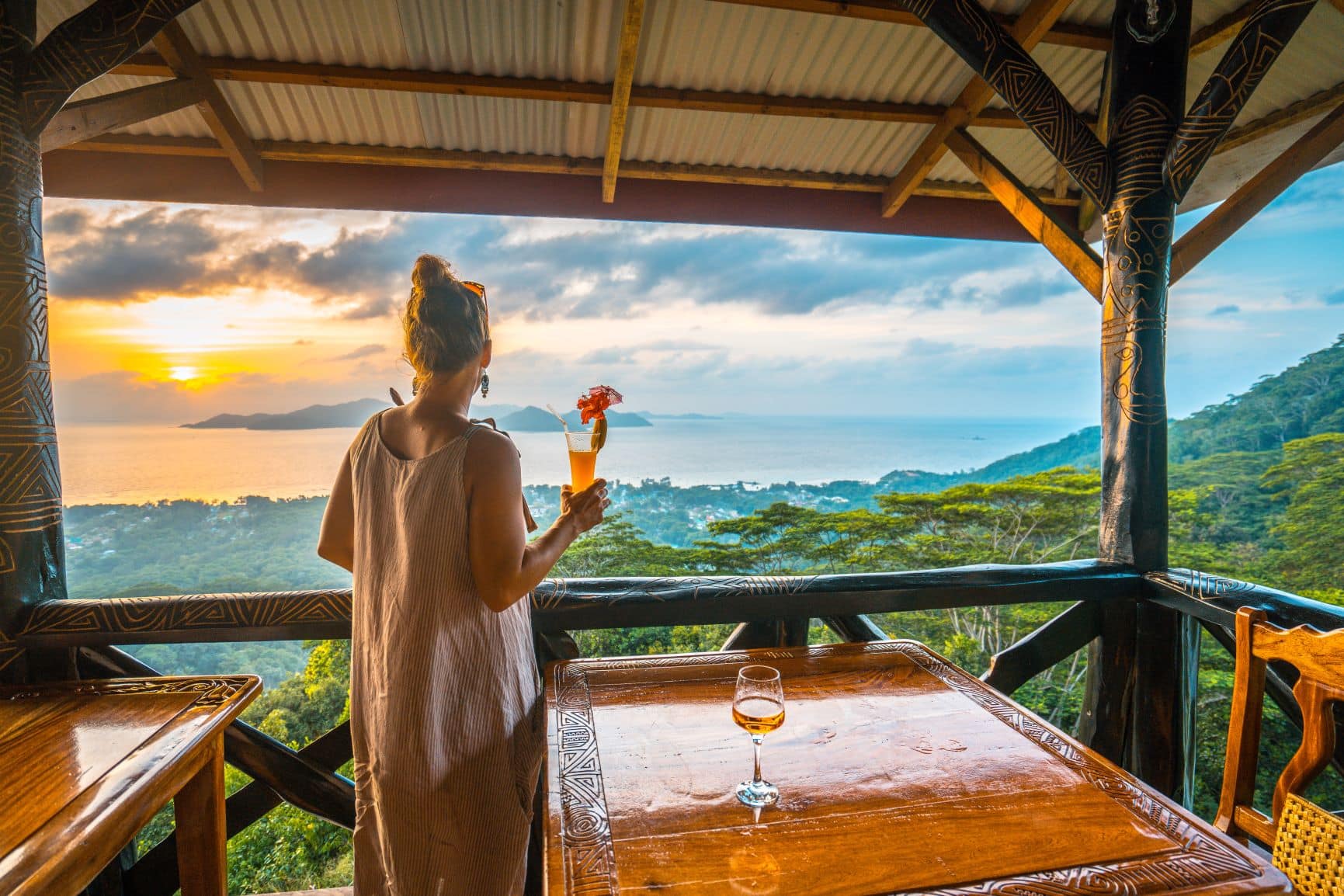 Frau mit Cocktail in der Hand auf einer Terrasse auf den Seychellen