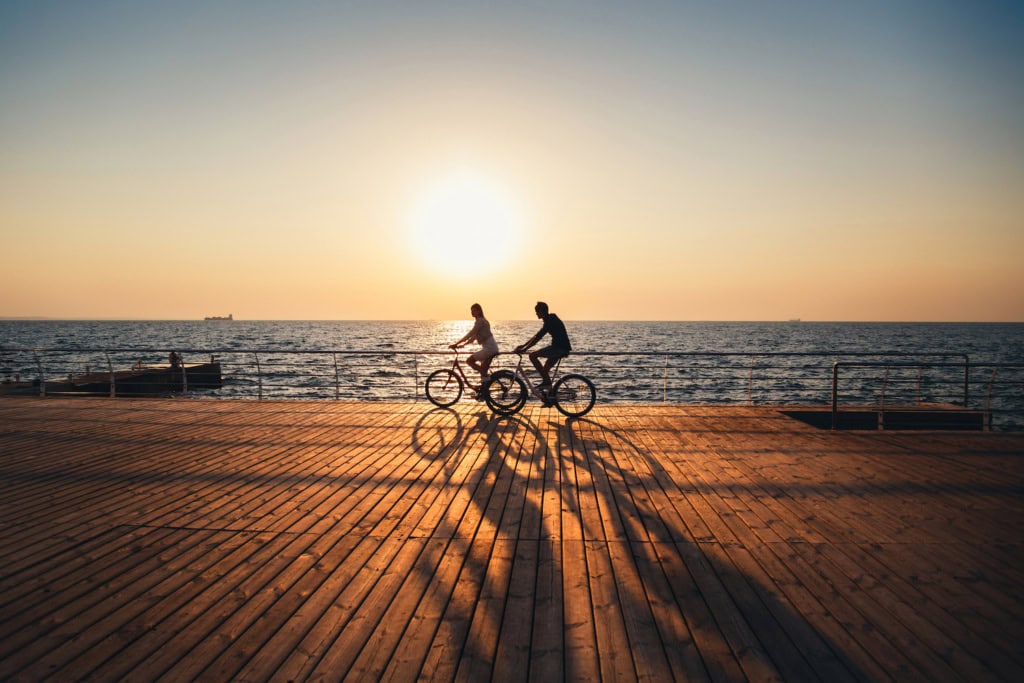 zwei Menschen bei einer Radtour am Meer in Deutschland beim Sonnenuntergang