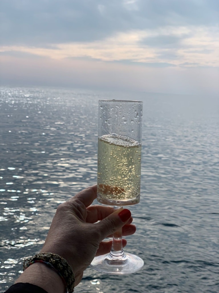 Frau hält Glas Sekt auf Yacht