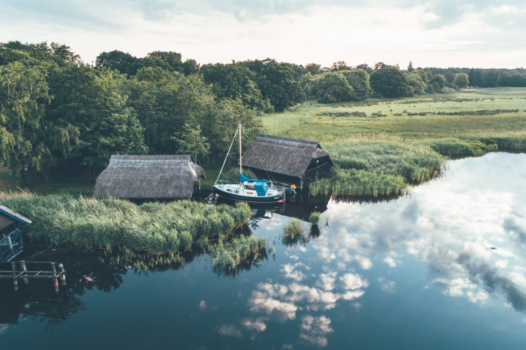 Yacht vor zwei Häusern in Seenlandschaft