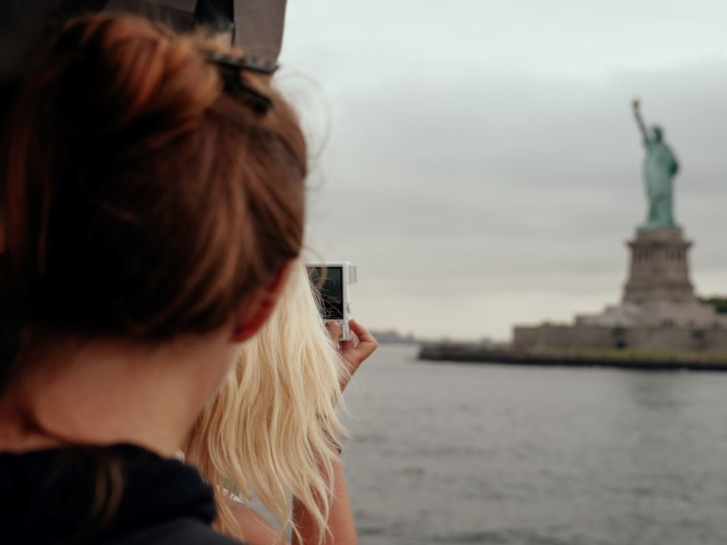 Frau fotografiert mit Handy Freihheitsstatue New York