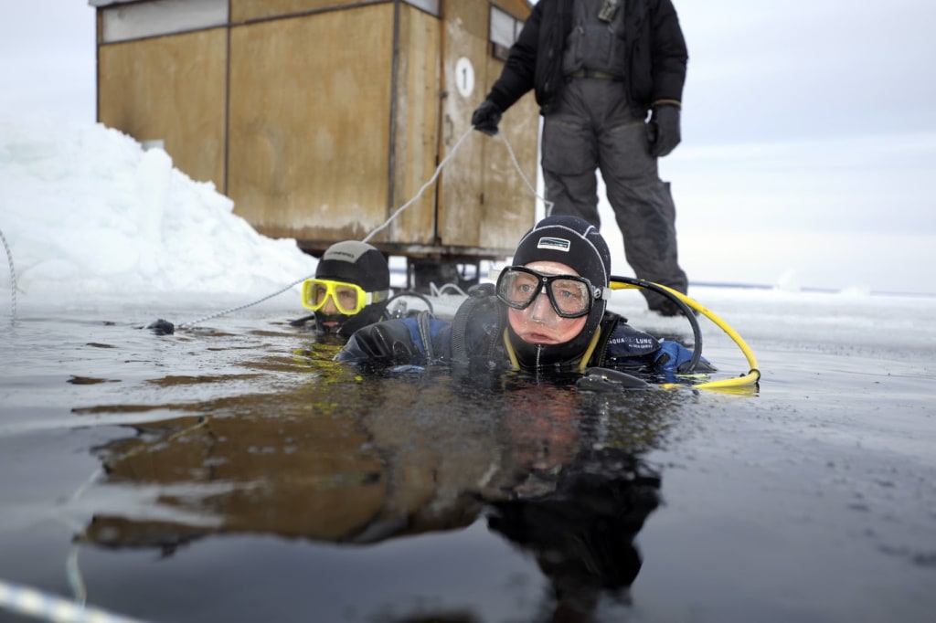 Taucher blickt aus Eiswasser