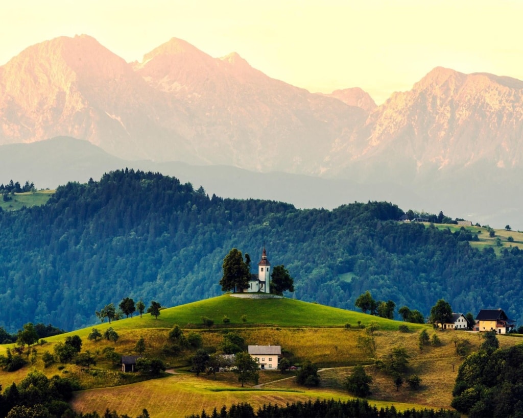 Urlaub in Slowenien: Kirche auf Hügel, im Hintergrund Berge