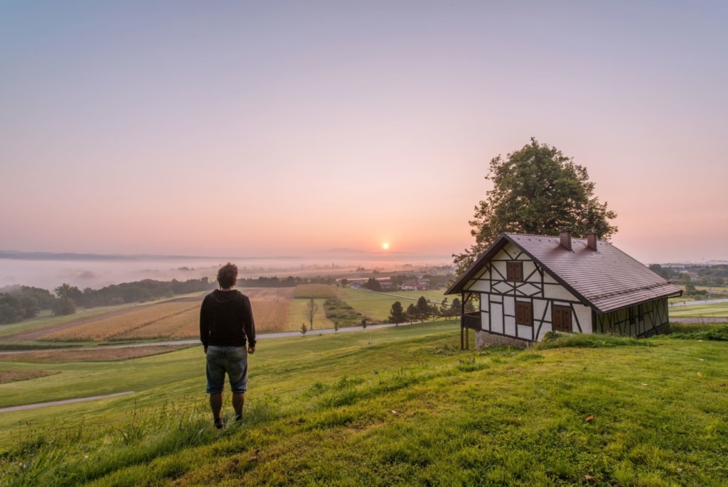 Mann steht auf Hügel und beobachtet Sonnenaufgang