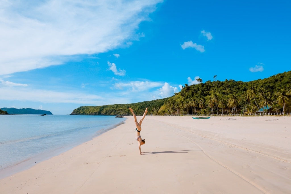 Frau macht Handstand am Strand