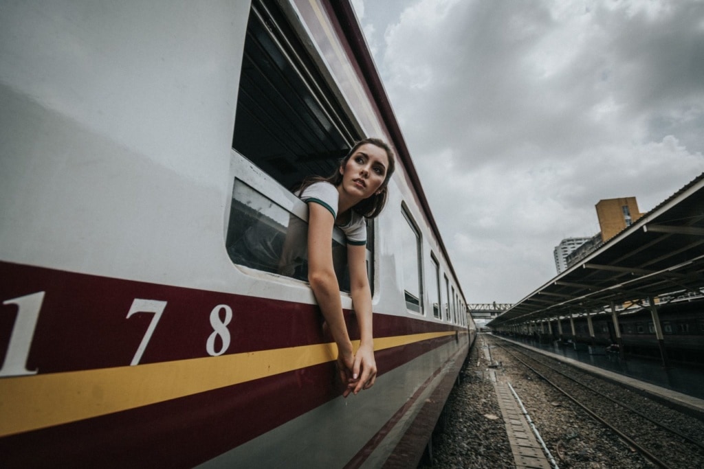 Junge Frau lehnt sich aus Zugfenster in Bangkok, Thailand