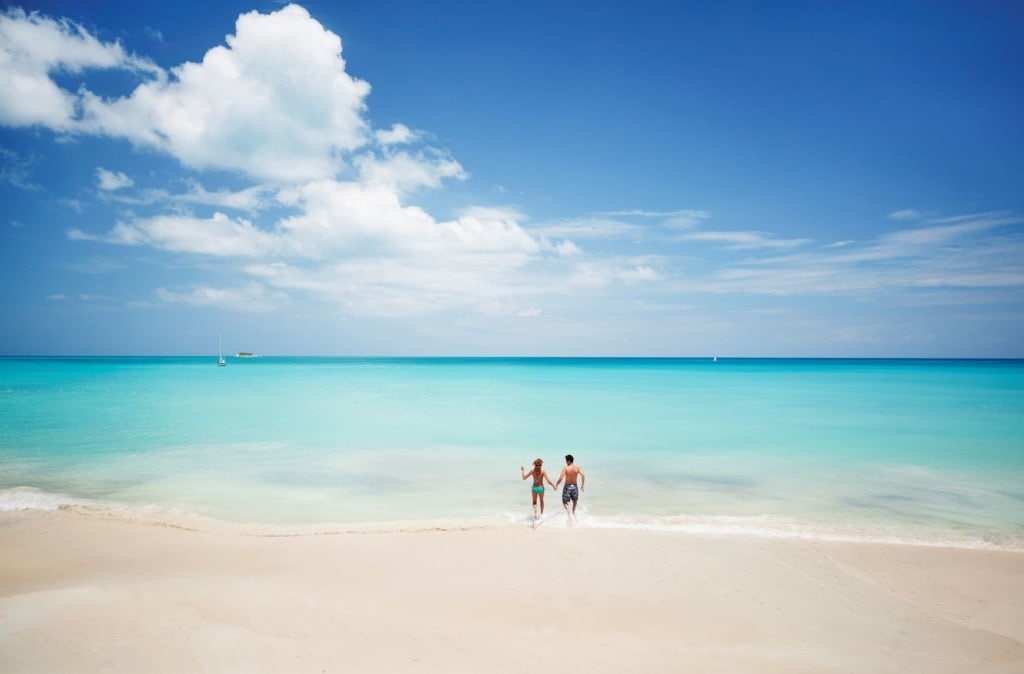 Paar auf Antigua läuft vom Strand ins Meer