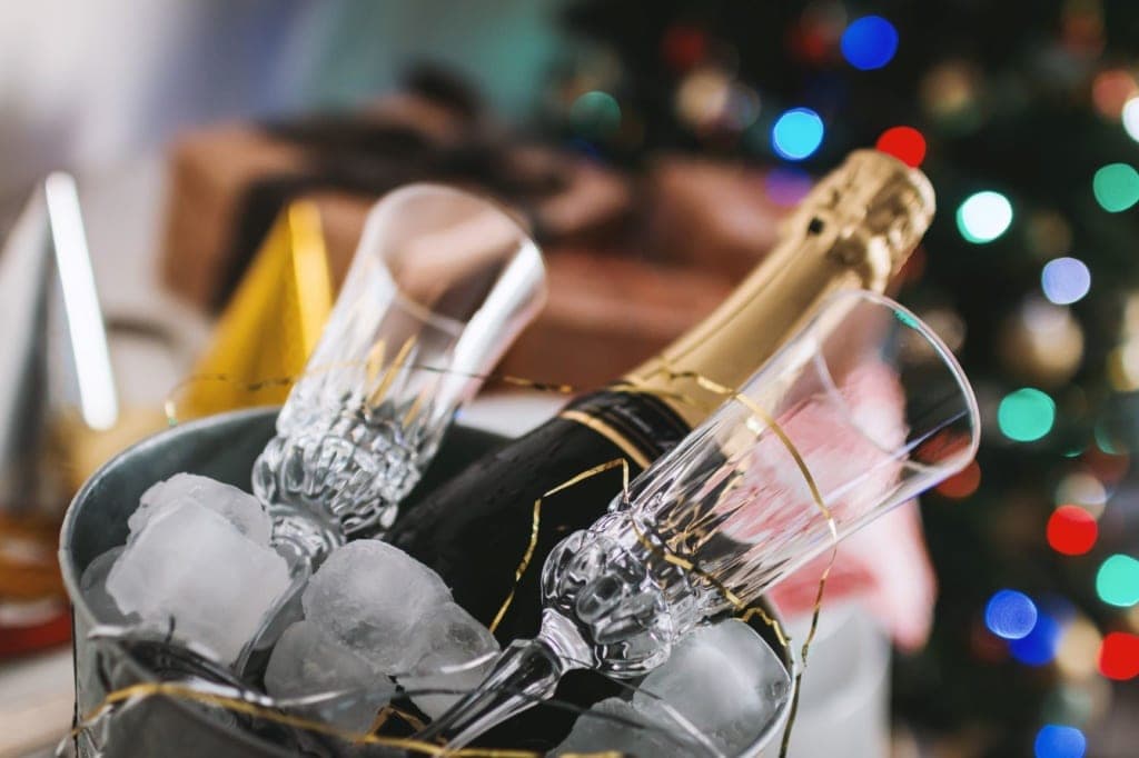 Flasche Champagner und Gläser in einem mit Eiswürfel befüllten Kübel