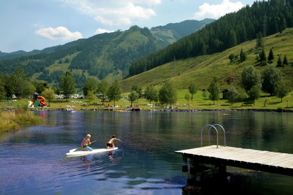 Kinder paddeln auf einem See im Sportcamp Woferlgut