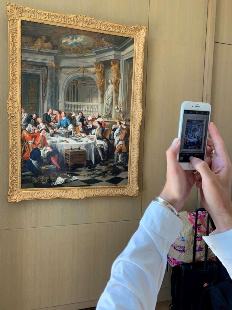 Frau macht Foto mit Handy von einem alten Gemälde