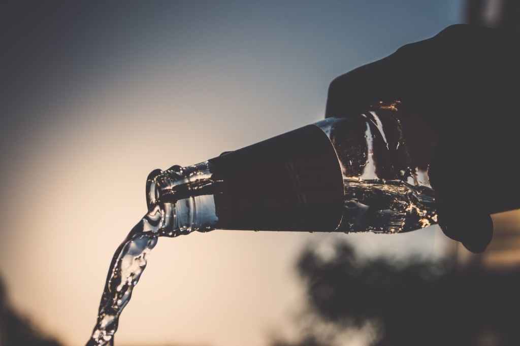 Jemand schüttet Wasser aus einer Flasche