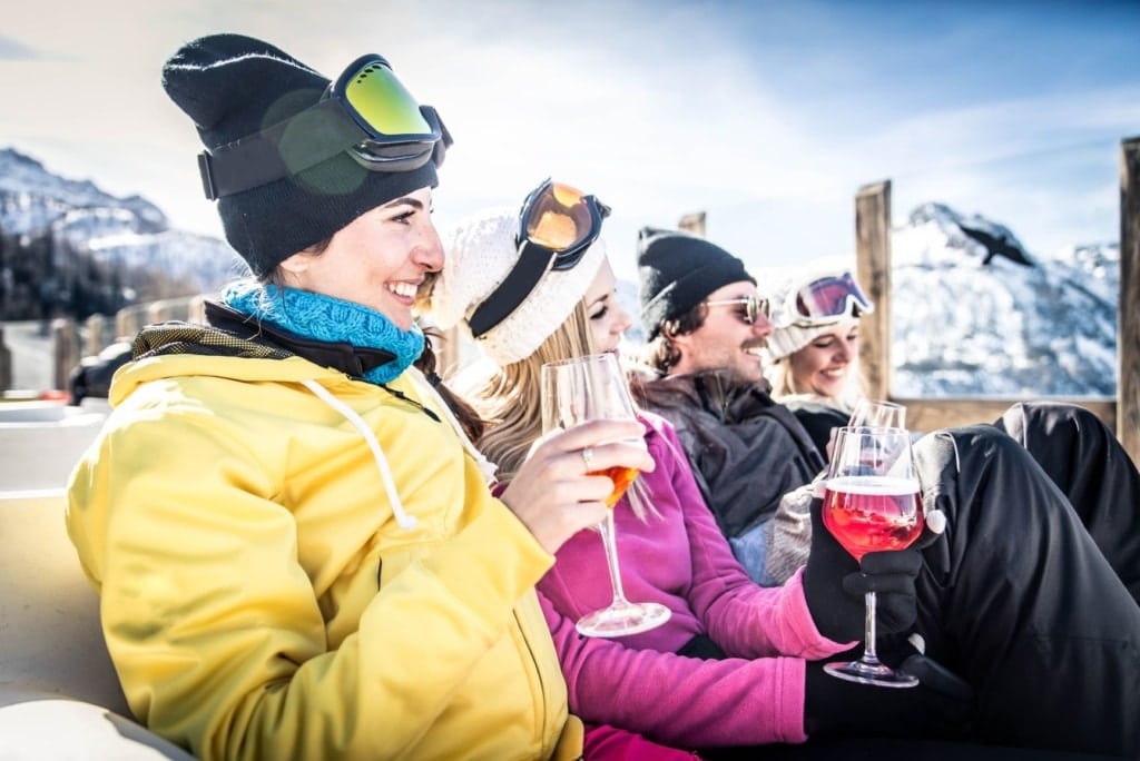 Skifahrer sitzen auf einer Terrasse und trinken Alkohol