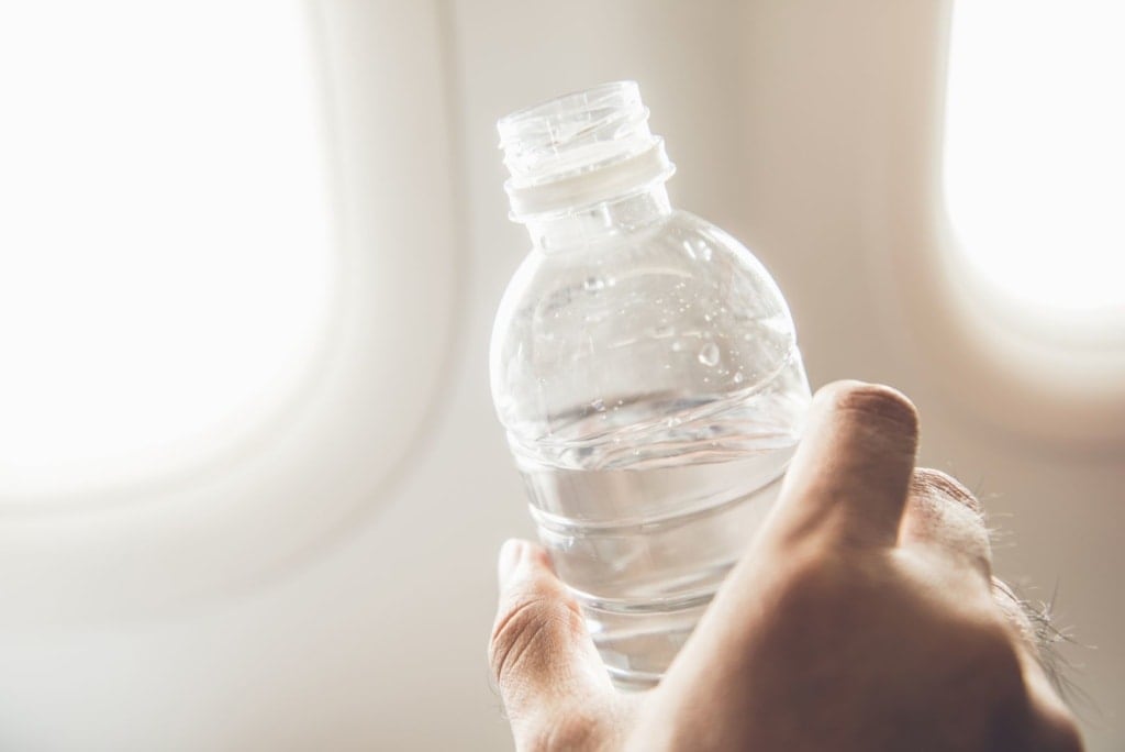 Hand eines Mannes hält Plastikflasche mit Wasser 
