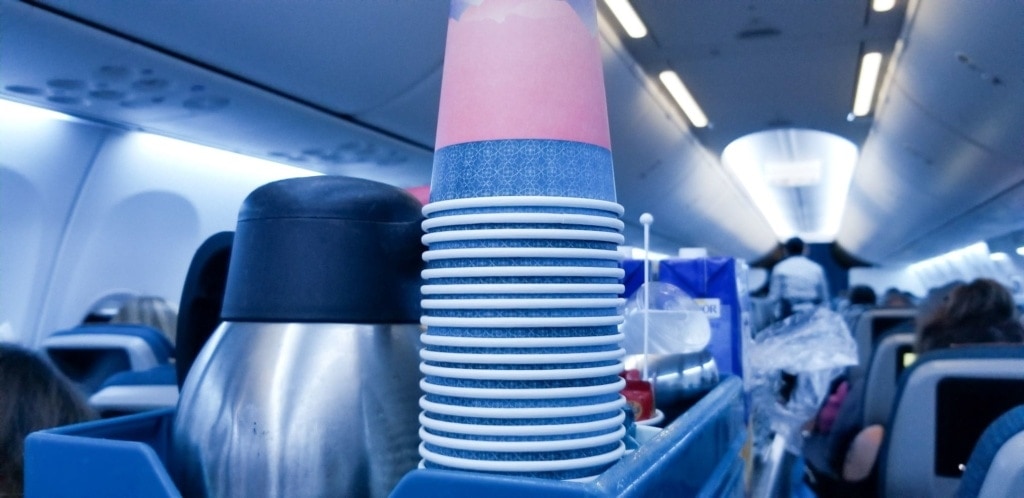 Pappbecher und Kaffeekanne auf Trolley im Flugzeug