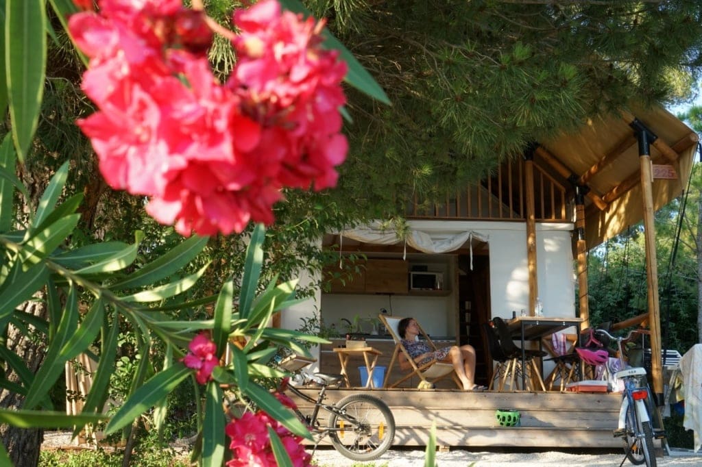 Frau auf Terrasse vor einem Zelt im One 99 Glamping